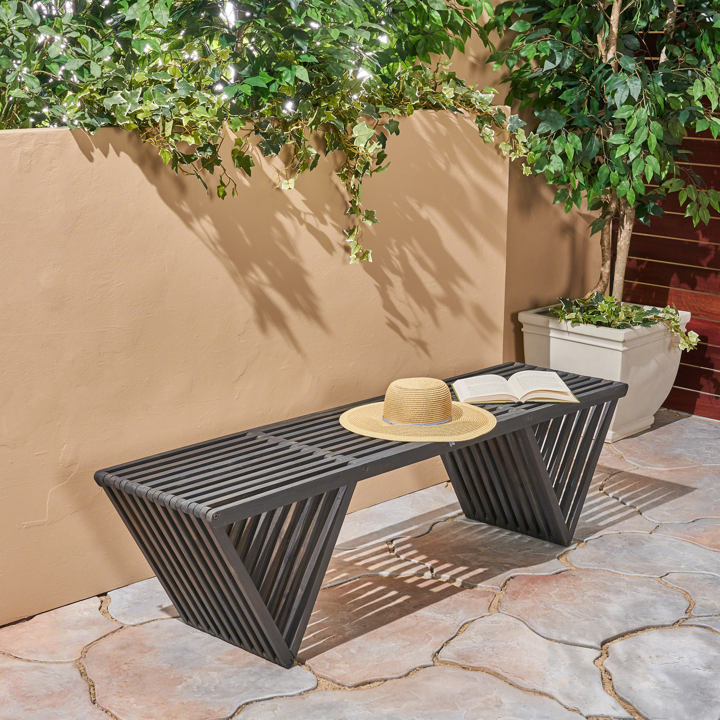 Weathered slatted bench with angled V-shaped legs on a stone patio