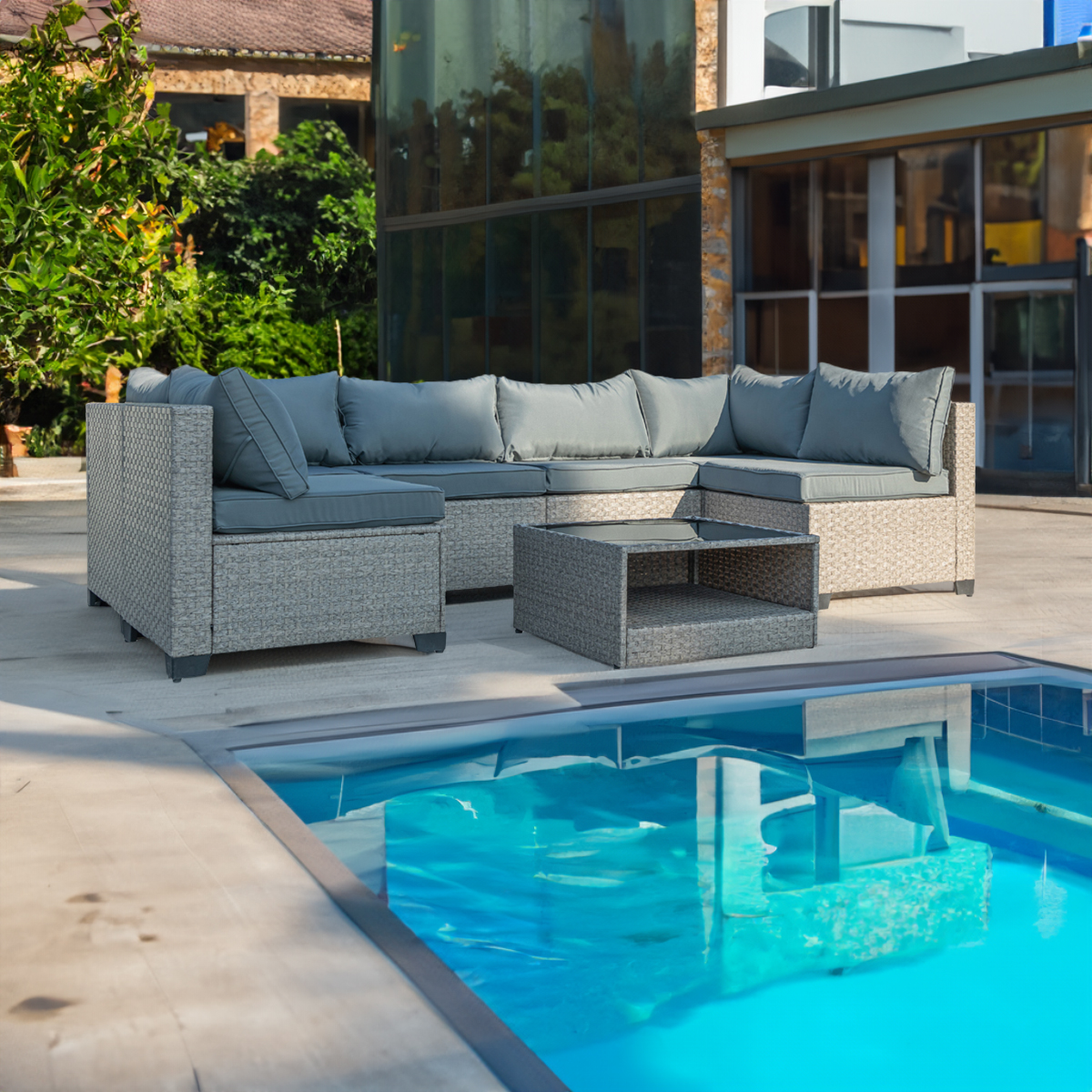 Grey rattan sectional set arranged around a table beside a pool