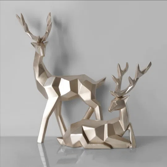 Champagne-gold standing and seated resin deer pair on grey backdrop