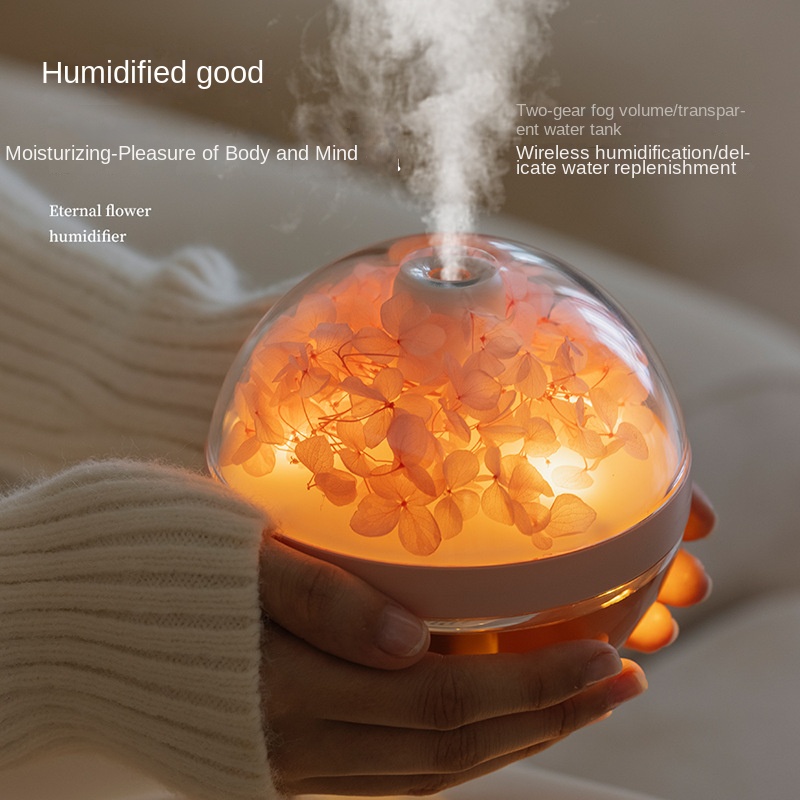 Hands cradling a flower humidifier with warm orange light and mist