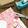 Wrapping a gift with pink floral wrapping paper, using scissors