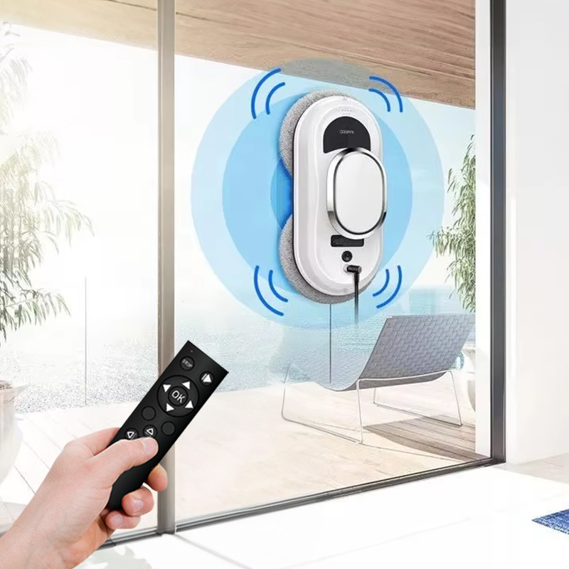 Hand grasping the slim black remote control, index finger on the directional pad, robot visible on window in background