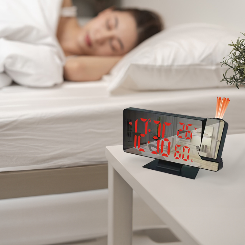 Projection alarm clock placed on a nightstand beside a bed