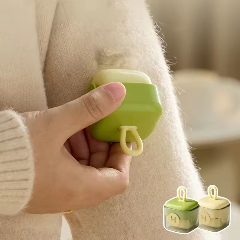 Hand holding a green square lint roller against a cream wool coat