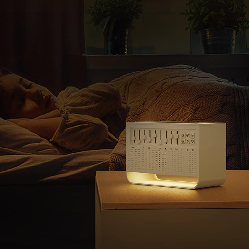 Person sleeping in a dim bedroom beside a glowing white sound unit