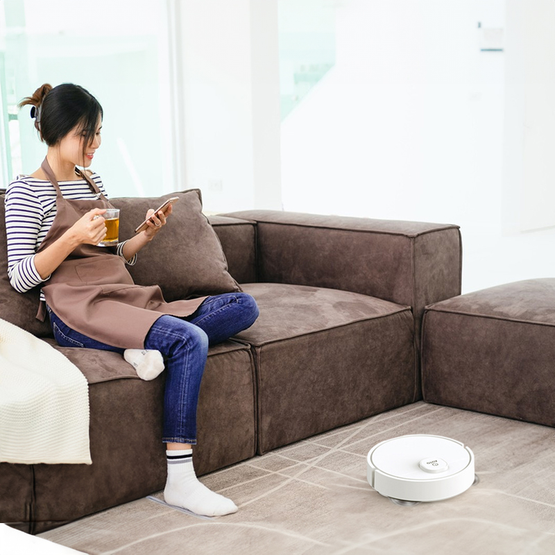 Slim robot vacuum disappearing under a sofa, only edge visible