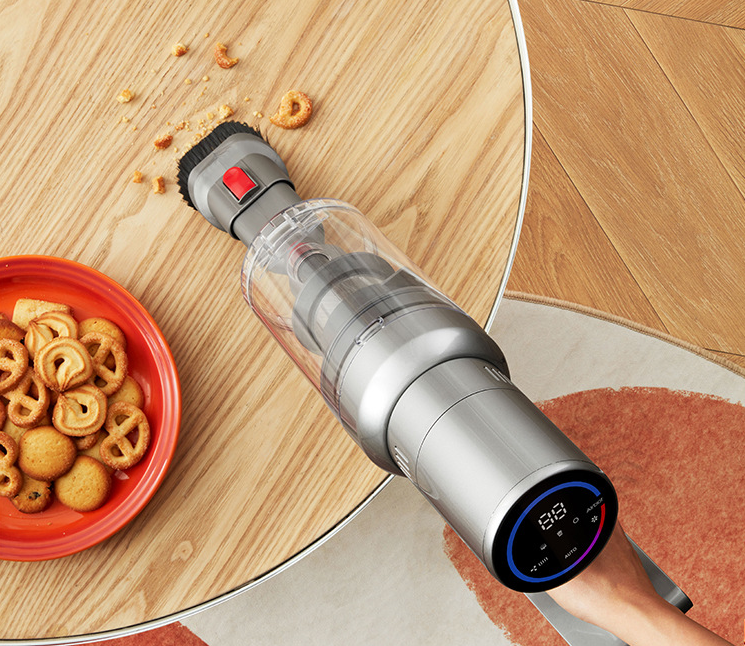 Handheld cordless vacuum on a wooden table beside a bowl of cereal