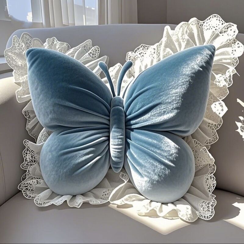 Dusty blue velvet butterfly pillow with white lace ruffles on a sofa