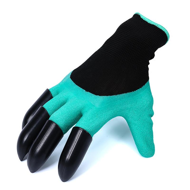 Palm of green gloves pressed into damp soil with black knit cuffs visible