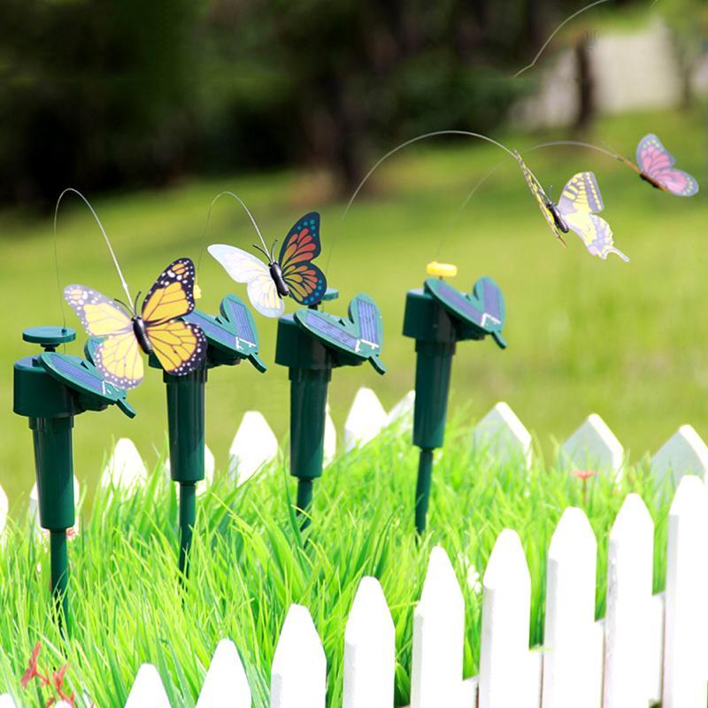 Several solar garden stakes with butterflies standing among white picket fence garden