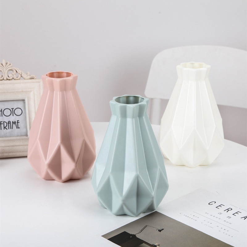 Pink, sage and white faceted vases lined up on a table