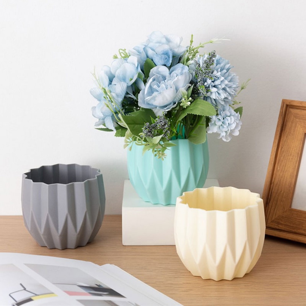 Grey, mint and cream faceted plastic vases on a wooden table with fresh flowers