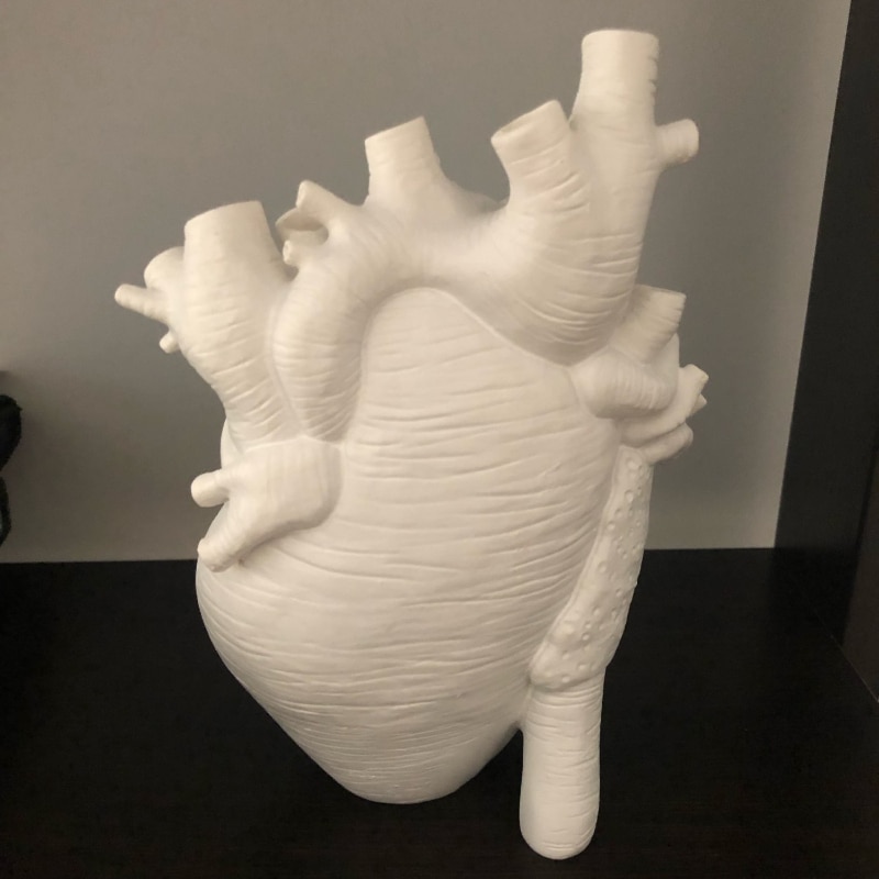 Side profile of white resin heart vase showing sculpted vessels and lobes