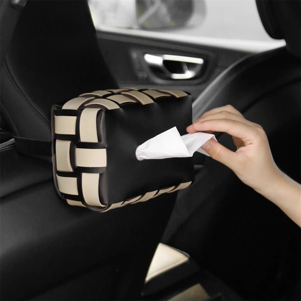 Woven tissue box hanging from a car headrest with a tissue being pulled