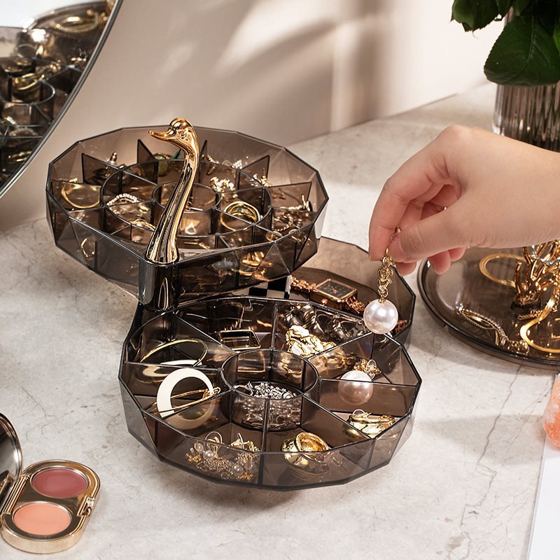 Open tiered swan organizer with rings and earrings placed in divided compartments