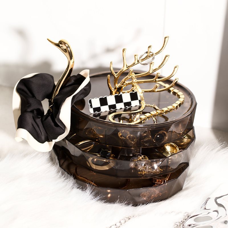 Gold antler rack holding necklaces and bracelets beside a styled swan organizer