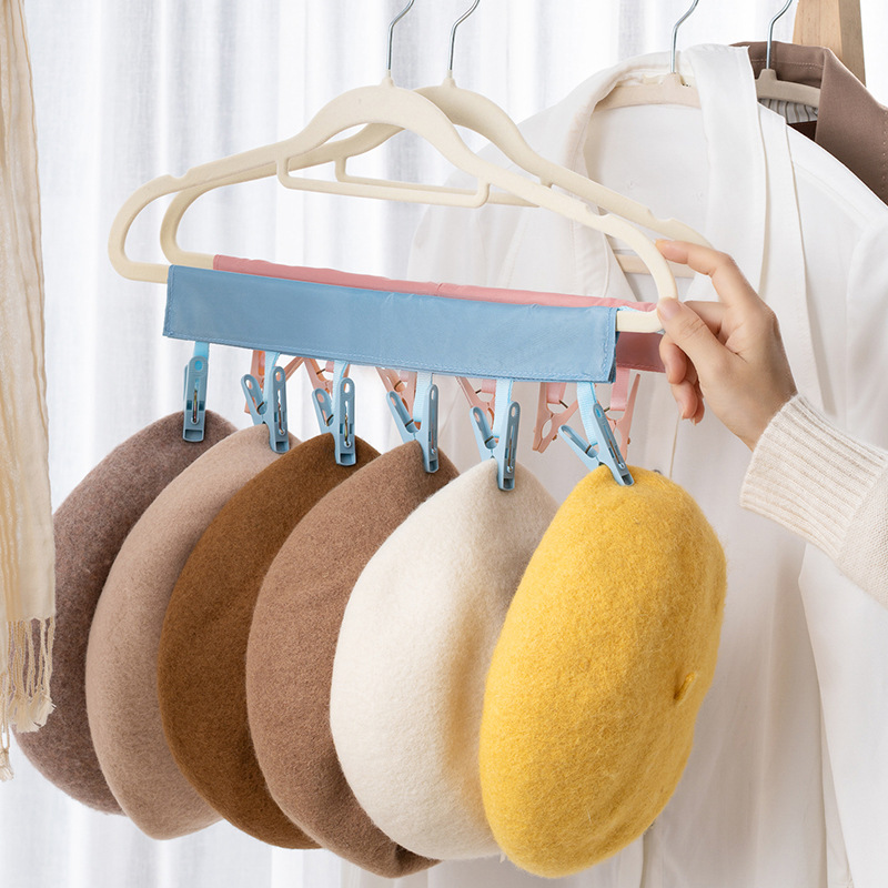 Hand hanging a blue clip hanger with berets in brown, tan and cream
