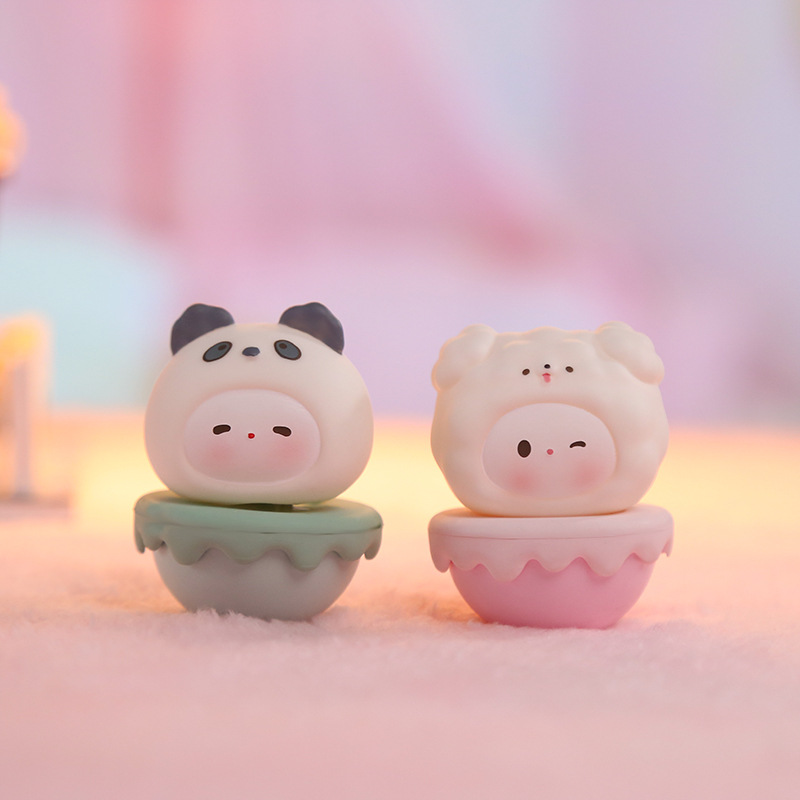 Panda and sheep wobbly figurines with expressive faces on soft pink
