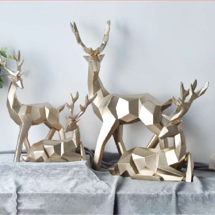 Gold geometric resin deer grouped on grey velvet in a styled room