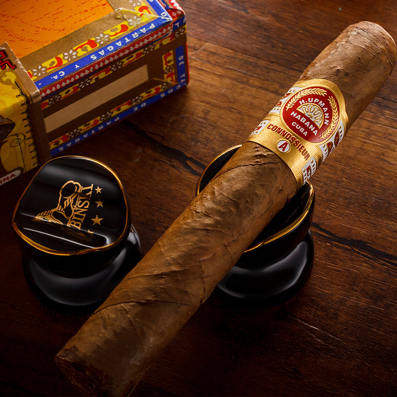 Black ceramic cigar holder with a cigar resting securely in the cradle