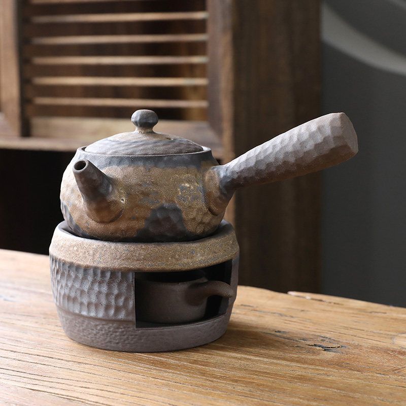 Teapot on tea warmer base with a small cup in the chamber