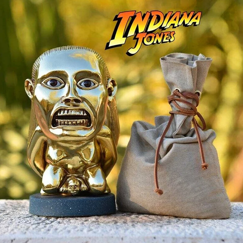 Gold idol statue placed outdoors beside a burlap pouch for a themed look