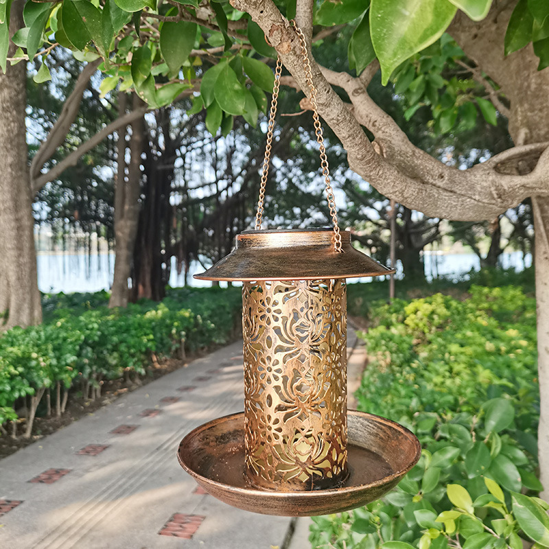 Copper feeder hanging from a tree branch over a garden path
