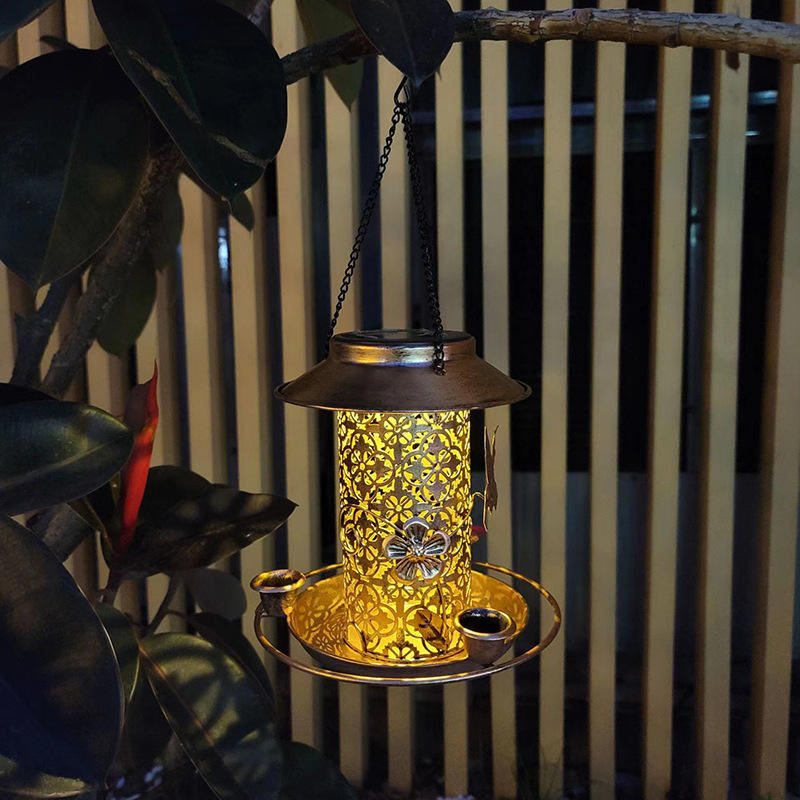Feeder hanging at night with warm gold glow through floral cutouts