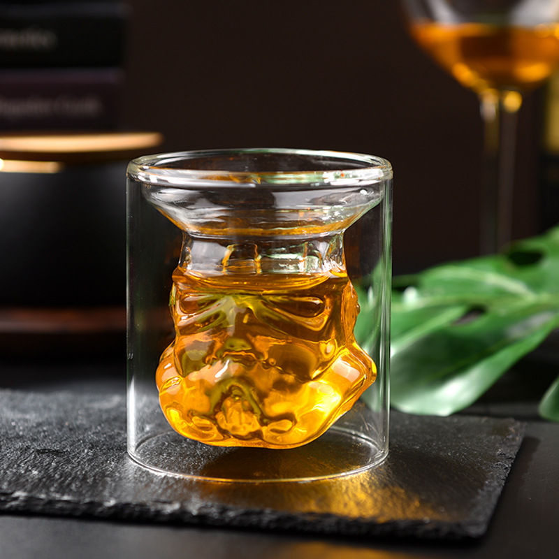 Stormtrooper helmet decanter standing on a light shelf beside a glass