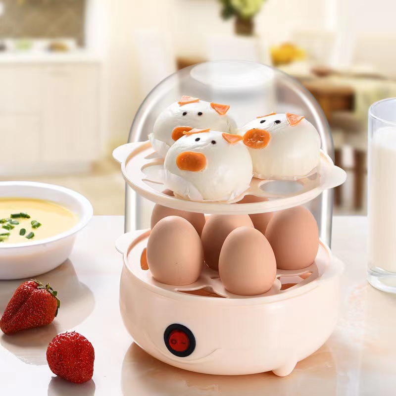 Two-tier egg cooker with buns on the upper tray and custard bowl nearby