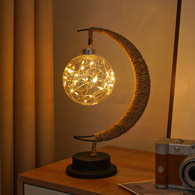 Hemp-wrapped moon lamp with clear glass ornament on a wooden bedside table