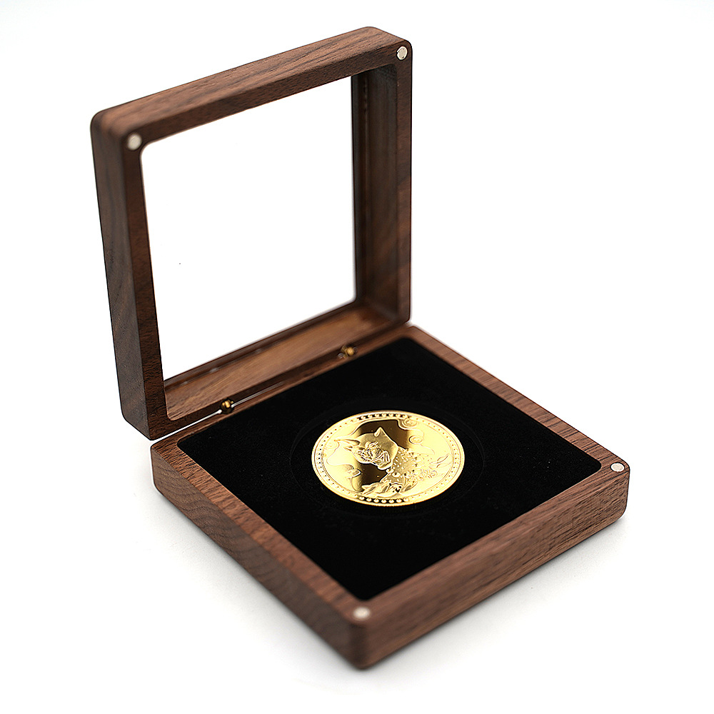 Open walnut box with glass lid raised, showing black velvet interior holding a gold coin