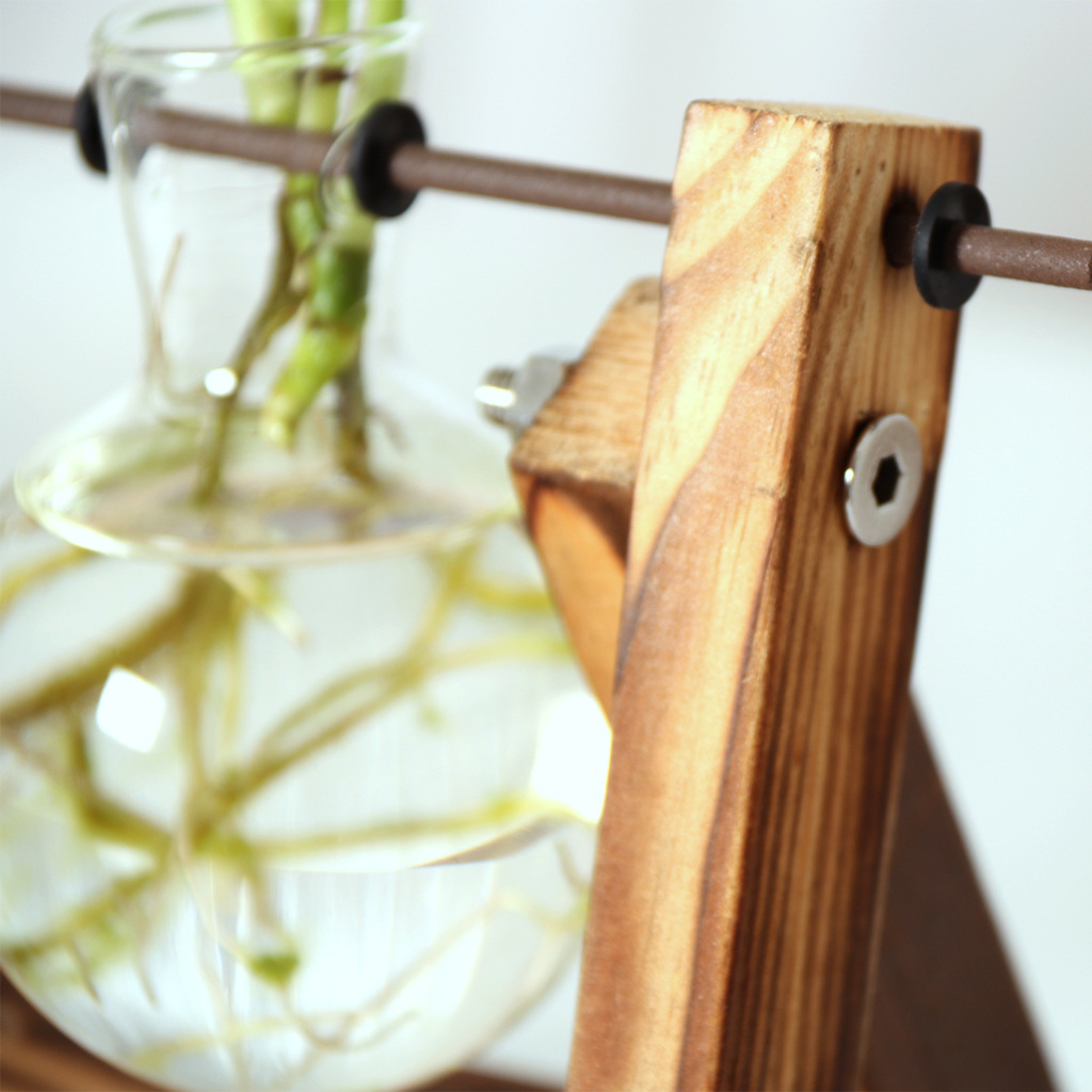 Close-up of glass bulb, black rod grommet and charred wood upright with metal screw