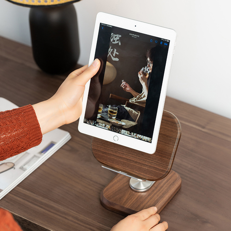 Hand placing a tablet into the walnut wood stand on a desk
