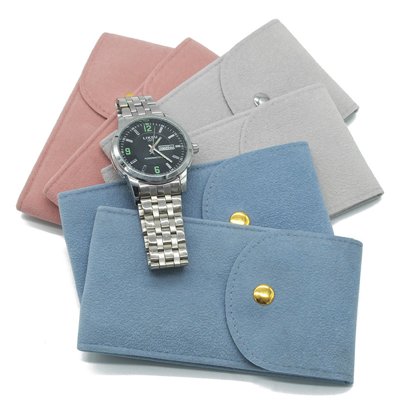 Lineup of velvet snap pouches in pink, grey and blue with a steel watch